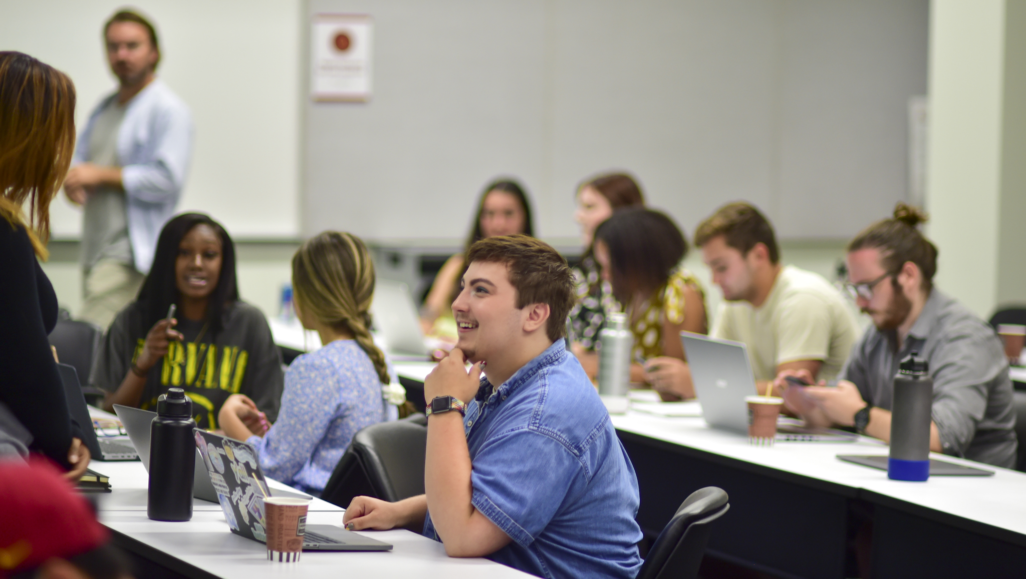 Students in a classroom, some studying and some talking to each other